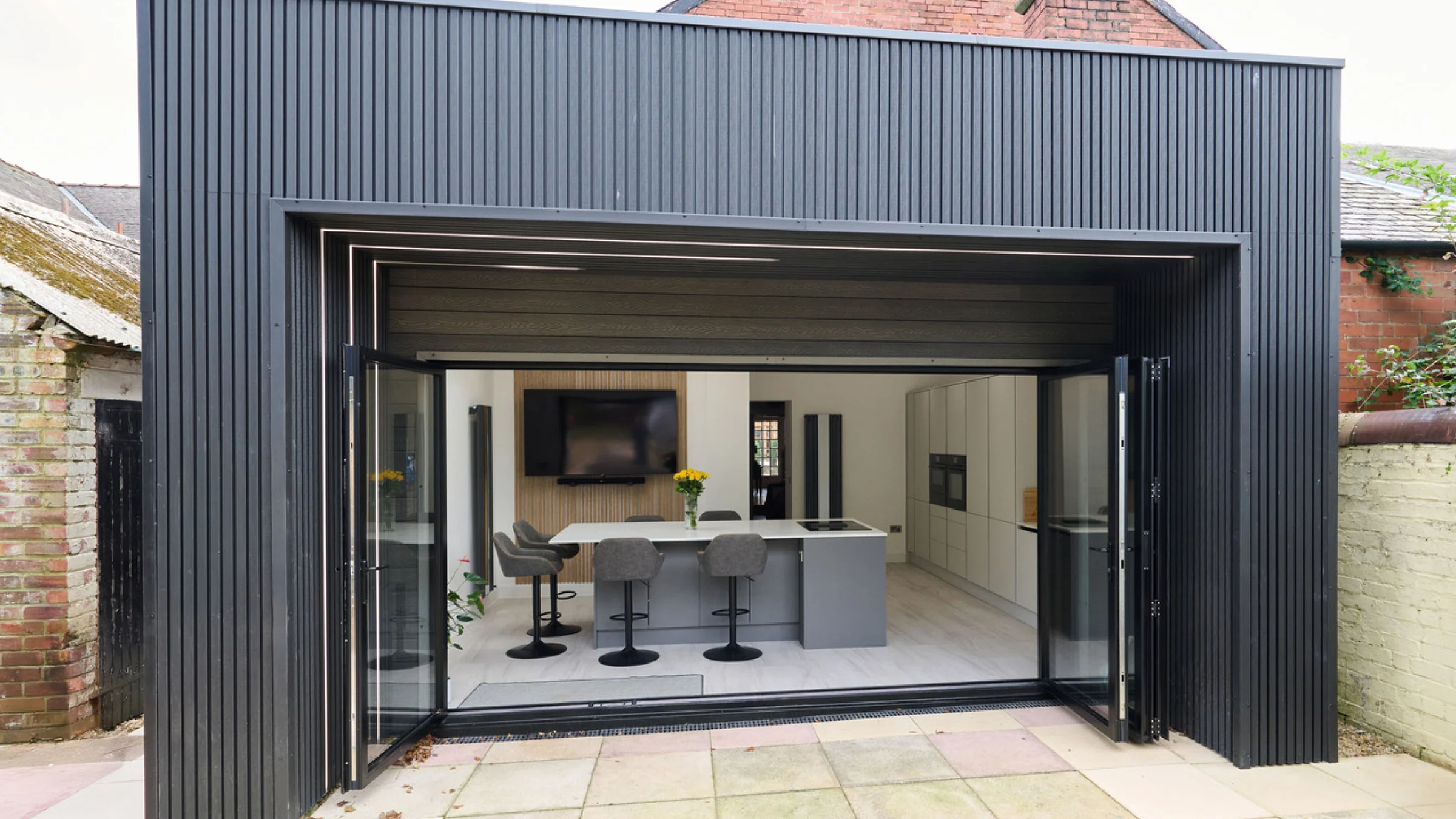 Black clad rear extension with bifold doors open to a new kitchen, Kilmarnock